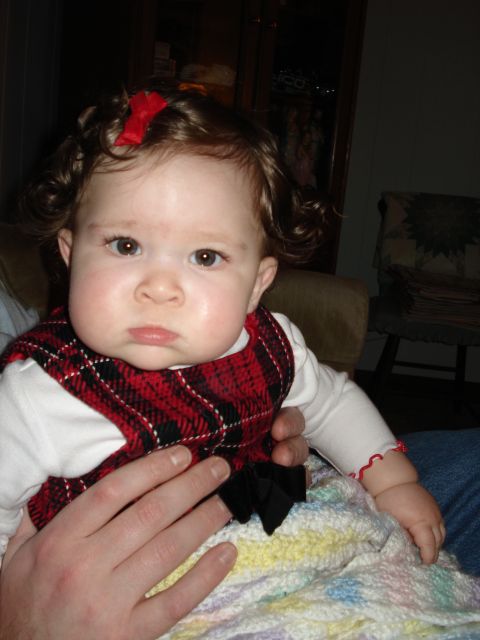 2000 Ford Crown Victoria - A baby girl with curly brown hair and a red bow in her hair is wearing a festive plaid outfit.