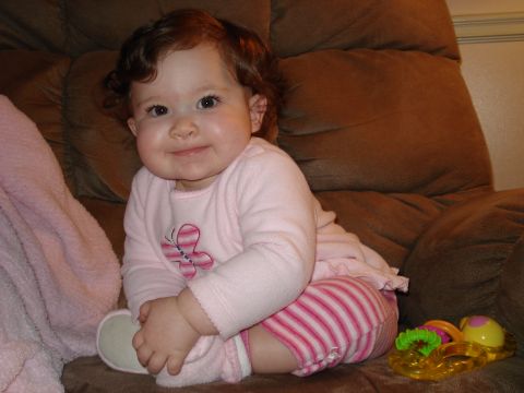 2000 Ford Crown Victoria - Baby girl sits on a couch, wearing a pink outfit with striped pants and a butterfly design.