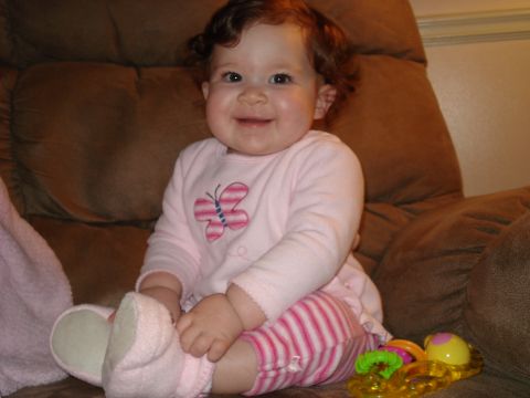 2000 Ford Crown Victoria - A baby girl smiles while sitting on a comfy chair with a butterfly on her shirt.