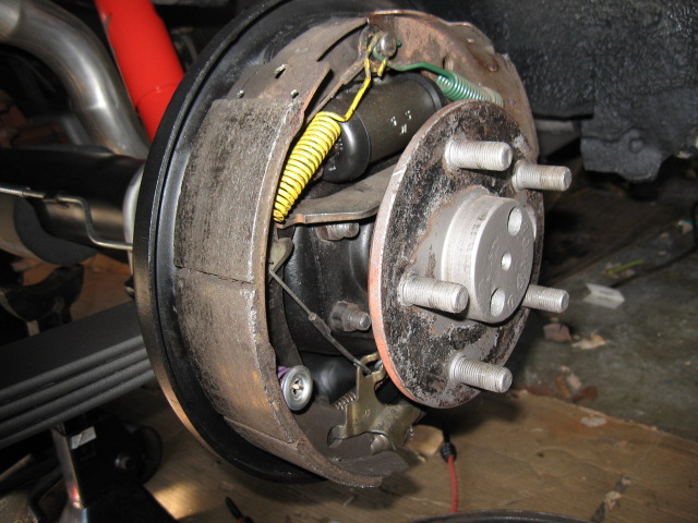 Rear drum brake assembly with red shock absorber and exhaust pipe