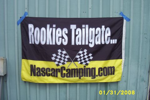 1993 Ford C-350 (Centurion Conversions) - A banner reading "Rookies Tailgate..." and "NascarCamping.com" with checkered flags is displayed on a corrugated metal wall.