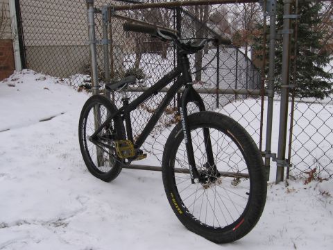 1997 Ford Probe - A black dirt jump bicycle is parked outside in the snow next to a fence.
