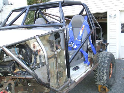 1995 Ford Bronco - Custom buggy build with roll cage and racing harness, showing exposed engine bay and door sill badge.