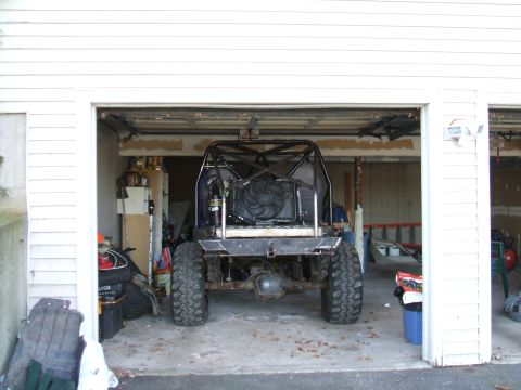 1995 Ford Bronco - Rear view of a heavily modified off-road vehicle with a roll cage, parked inside a garage.