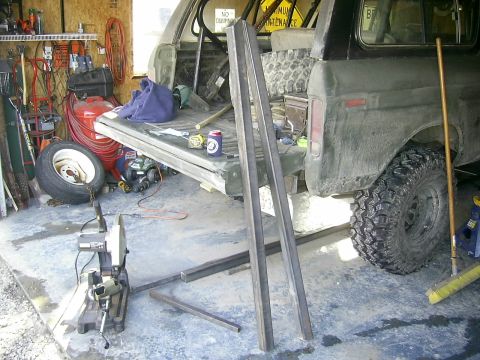 1978 Ford Bronco - A Ford Bronco is parked in a garage with its tailgate open, surrounded by tools and metal stock for fabrication.