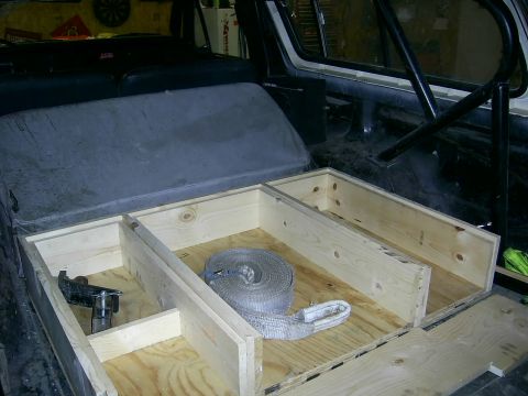 1978 Ford Bronco - Interior view of a vehicle showing a custom wooden storage box and seat, behind it, a gray seat.