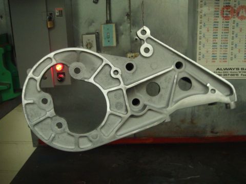 1996 Ford Bronco - A metal bracket with a red indicator light is shown against a background of a chart and industrial equipment.