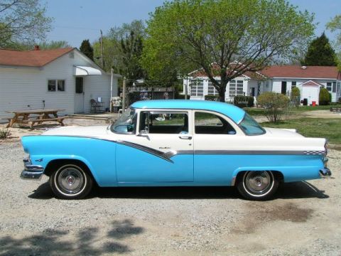1956 Ford Fairlane - A two-tone blue and white 1956 Ford Fairlane sedan parked in a gravel driveway.