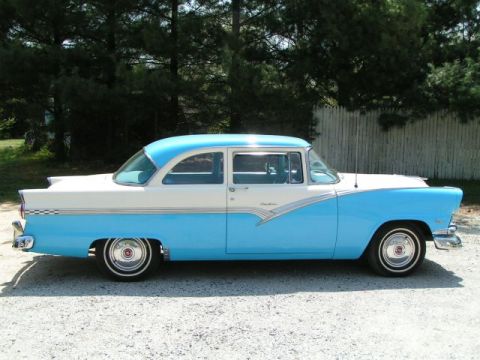 1956 Ford Fairlane - A two-tone blue and white 1956 Ford Fairlane sedan is shown from the side, parked outdoors.