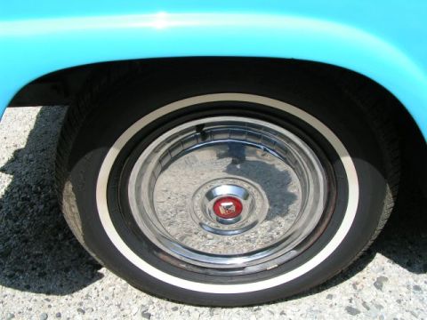 1956 Ford Fairlane - A detail shot focuses on the whitewall tire and hubcap of a vintage automobile.