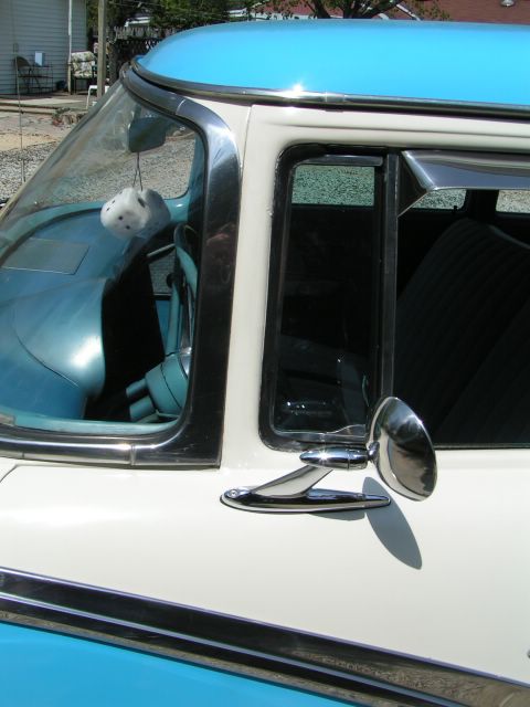 1956 Ford Fairlane - The side view of a 1956 Ford Fairlane reveals its two-tone paint scheme and a glimpse of the interior with dice hanging from the rearview m…