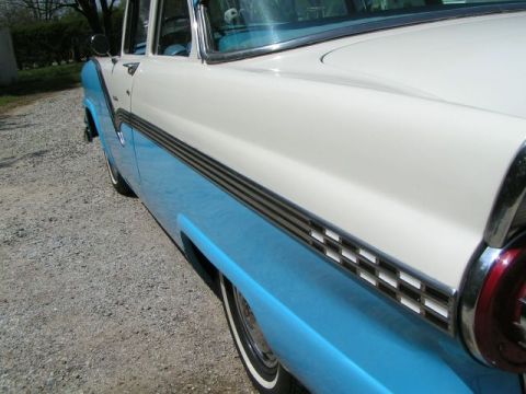 1956 Ford Fairlane - A classic two-tone blue and white 1956 Ford Fairlane is viewed from the side, highlighting its distinctive chrome trim and tail light.