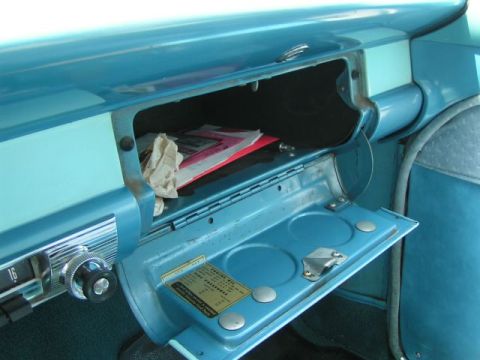 1956 Ford Fairlane - The interior of a 1956 Ford Fairlane shows an open glove box with documents and a sticker inside.