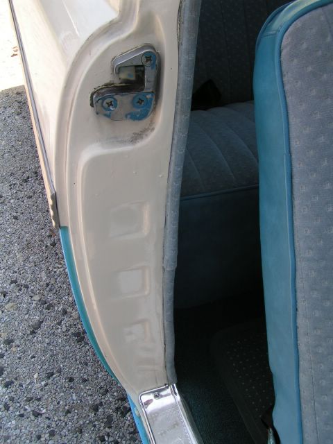 1956 Ford Fairlane - The interior of a car shows a blue patterned seat and the door latch mechanism.