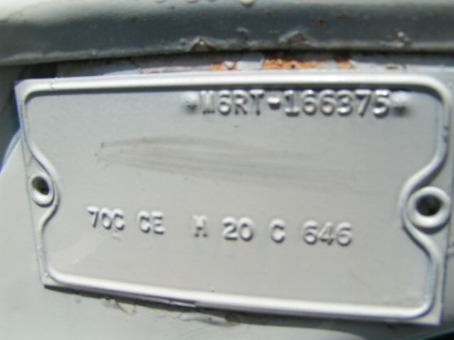 Close-up of a vehicle identification plate with stamped numbers and letters