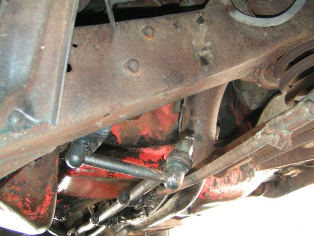 Undercarriage view of rusty frame and suspension components, possibly from an older car