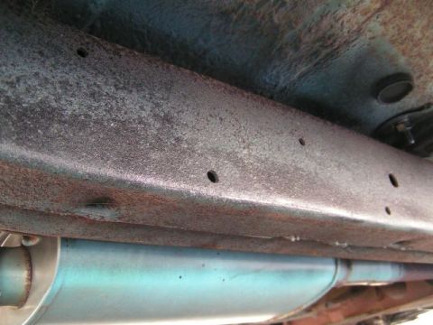 1956 Ford Fairlane - The underside of a vehicle, showing the frame and exhaust system, with visible signs of rust.