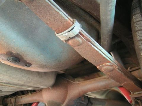 1956 Ford Fairlane - The undercarriage shows significant rust on the leaf spring and differential, with a tire in the background.