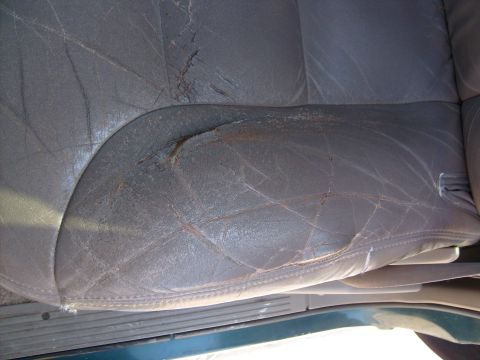 1995 Ford C-350 (Centurion Conversions) - The leather upholstery on this car seat shows significant wear and tear, with multiple cracks and a large rip.