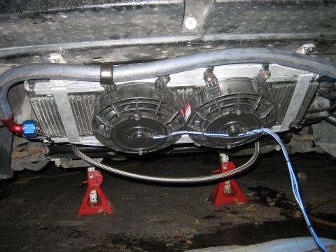 1996 Ford Thunderbird - This photo shows an aftermarket oil cooler with dual fans installed underneath a vehicle, which is raised on jack stands.