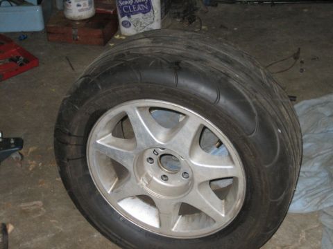 1996 Ford Thunderbird - A close-up view of a tire mounted on a silver alloy wheel, likely in a garage or workshop environment.
