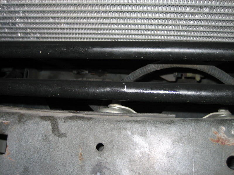 Radiator and black metal bars above a gray metal frame with visible bolts and wiring