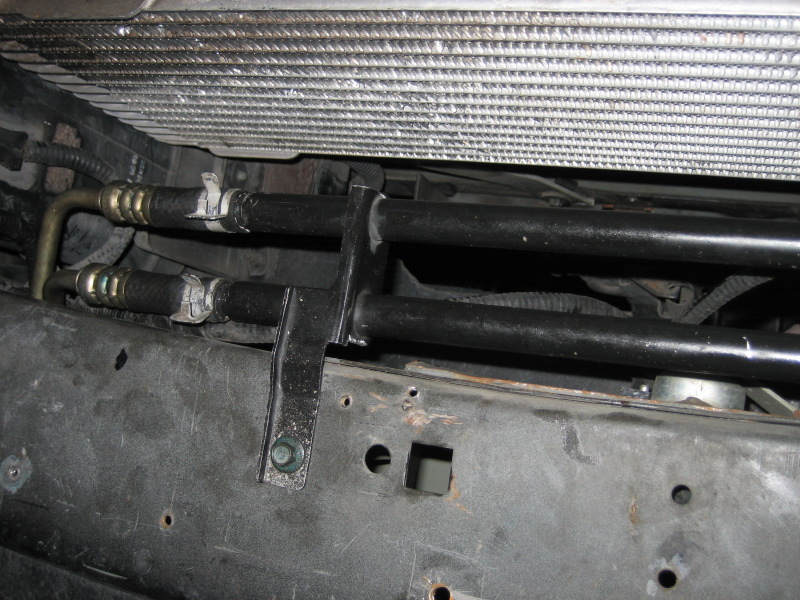 Radiator and AC condenser lines connected to a bracket, with part of the radiator visible above