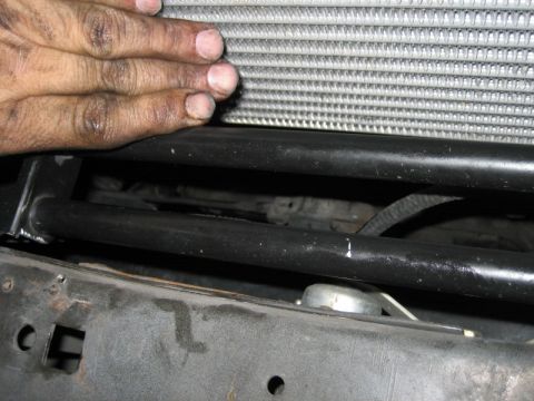 1996 Ford Thunderbird - A close-up view of a vehicle's radiator and front frame structure, with a hand resting on the top.