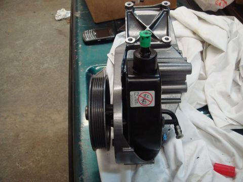 1996 Ford Bronco - A power steering pump with its pulley attached sits on a green surface, partially covered by white cloth.