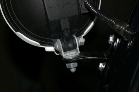 1986 Ford Bronco - Detail of a headlight assembly mount, showing hardware and electrical connection.