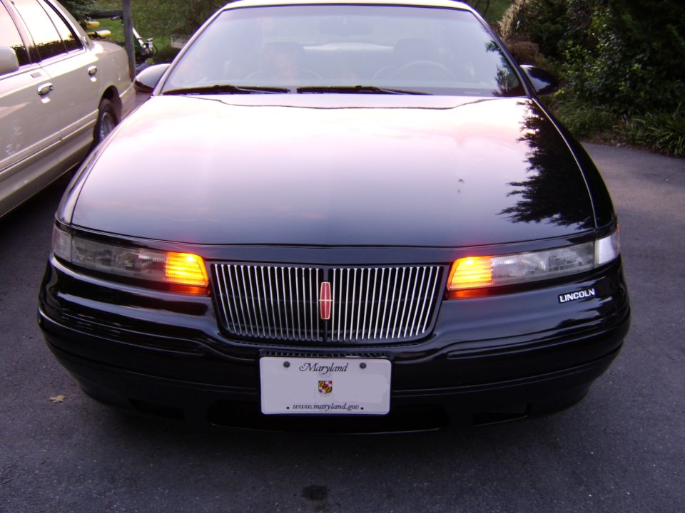 Front of black Lincoln sedan with chrome grille and Maryland plate, turn signals on