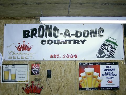 1978 Ford Bronco - A banner hangs on a wood-paneled wall, advertising "BRONC-A-DONC COUNTRY" with a graphic of a green off-road vehicle.