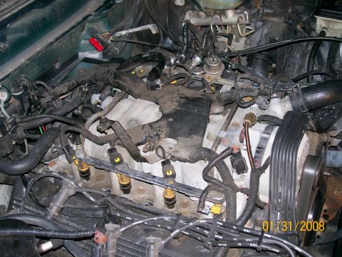 1995 Mercury Grand Marquis - Top-down view of a V6 engine with the intake manifold removed, exposing the aluminum cylinder heads, fuel injectors with visible rails, and…