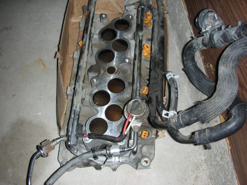 1998 Ford Crown Victoria - Aluminum lower intake manifold with six open runner ports, fuel rail and engine wiring on cardboard.
