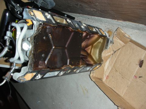 1998 Ford Crown Victoria - Inside view of a removed engine oil pan with sealant on the rail edges, laid on a concrete floor.