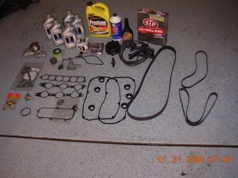 1995 Ford Taurus - Collection of engine maintenance parts and fluids, including oil, coolant, and various gaskets and belts.