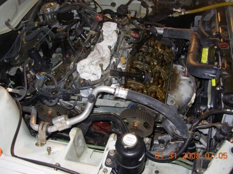 1995 Ford Taurus - Close-up view of a car engine with various parts exposed, including hoses and timing gears.
