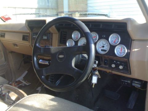 1985 Ford Bronco - The interior of this vehicle features a steering wheel and a dashboard equipped with several aftermarket gauges.