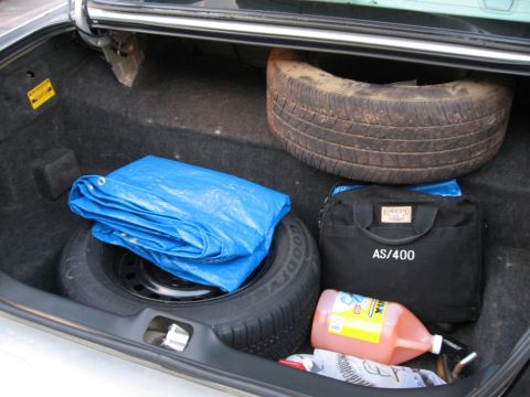 2004 Ford Crown Victoria - Trunk contents include a spare tire, blue tarp, and a tool bag with AS/400 label.