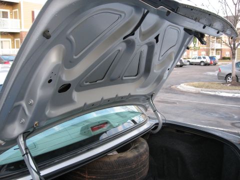 2004 Ford Crown Victoria - The underside of a car's trunk lid is shown, with a spare tire visible in the trunk below.