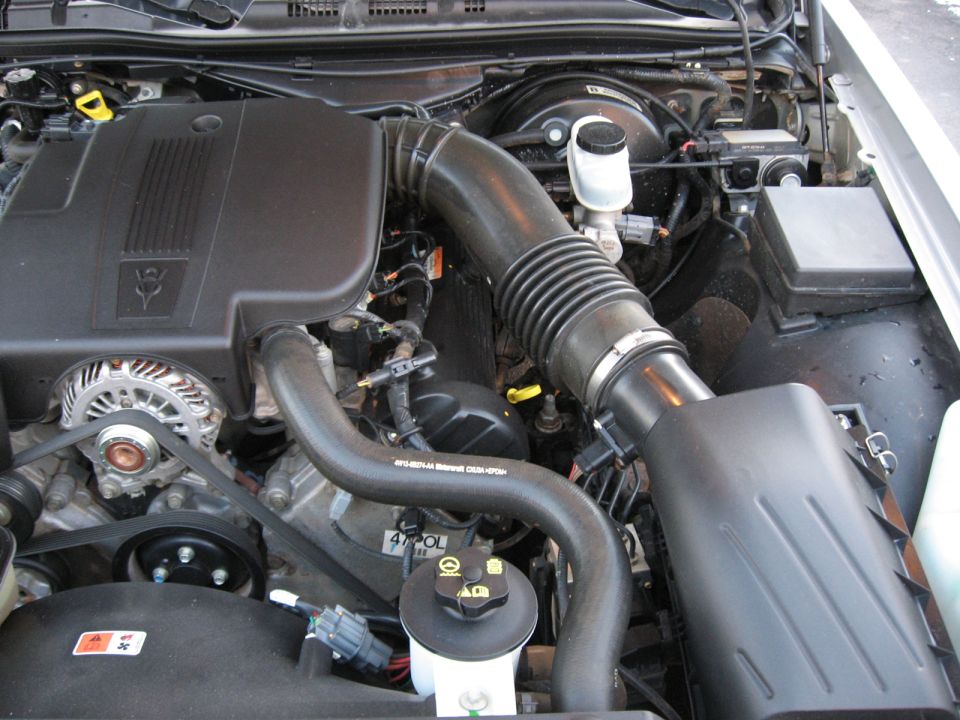2004 Ford Crown Victoria engine bay with black plastic covers, alternator, and hoses