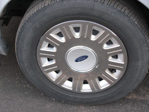 2004 Ford Crown Victoria - This image shows a close-up of a Ford wheel, a silver hubcap with the iconic blue Ford logo in the center.