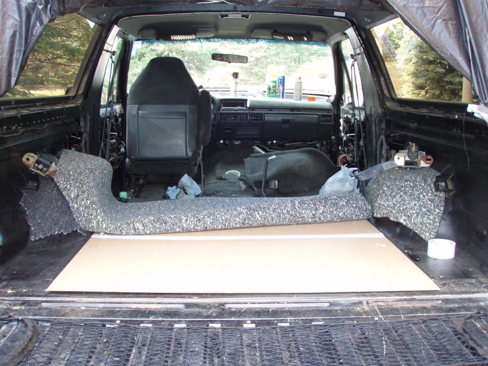 Stripped SUV cargo area with rear seat removed showing bare floor and carpet pulled back