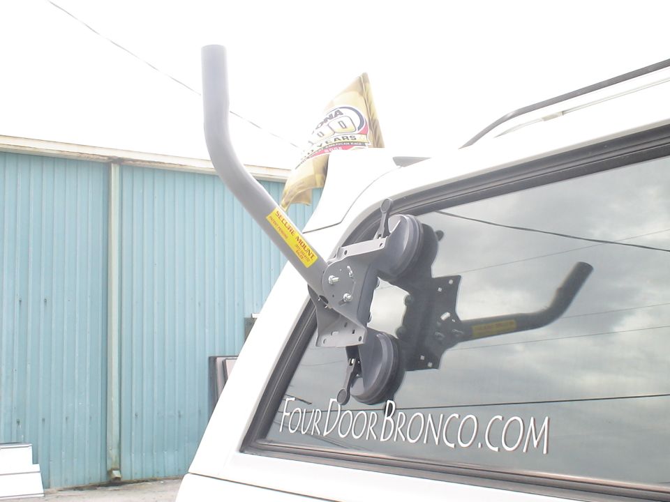 White SUV rear window with a suction cup mount holding a satellite dish arm. Text reads "FOUR DOOR BRONCO.COM"