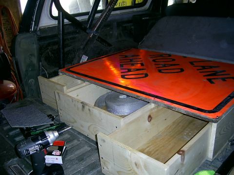 1978 Ford Bronco - Custom wooden storage drawers are installed in the rear of a vehicle, holding a large orange traffic sign.