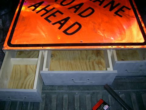 1978 Ford Bronco - Custom storage drawers are fitted into the bed of a pickup truck, positioned below a large orange traffic sign.