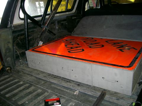 1978 Ford Bronco - A traffic sign reading 'Road Ahead Lane' is stored inside a vehicle's cargo area on top of a custom storage box.