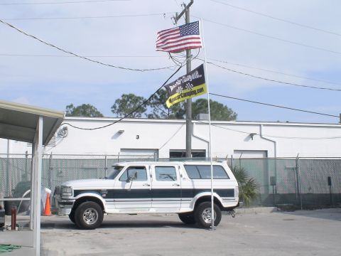 1993 Ford C-350 (Centurion Conversions) - This extended SUV, likely a 1992 model, is parked in front of a commercial building.