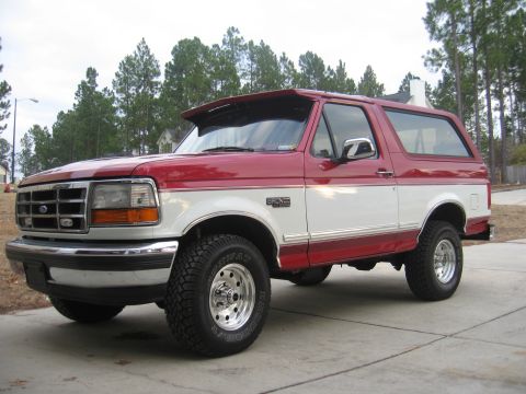 1995 Ford Bronco - This two-tone red and white Ford Bronco is shown from a three-quarter front view, parked on a concrete driveway.