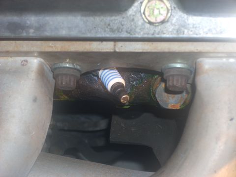 1991 Ford Mustang - Close-up view of a spark plug inserted into an engine block.